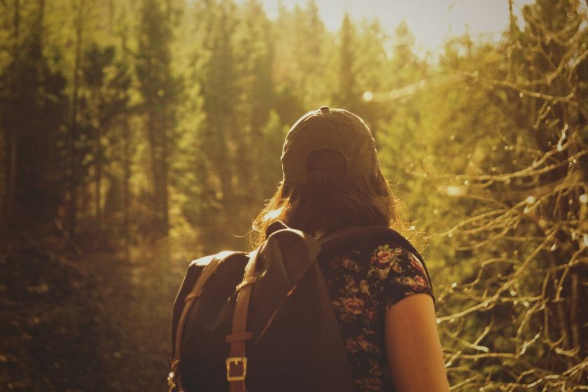femme portant un sac à dos et regardant au delà des arbres